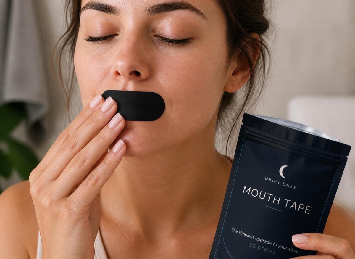 Woman applying a Drift Easy Mouth Tape strip to her lips before bed